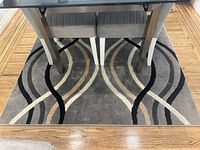 Overview of the carpet under a table, showing the full pattern and condition.