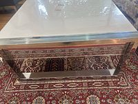 Side view of white coffee table with metal frame placed on a patterned rug.