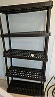 Front and side views of the black collapsible plastic shelf showing five evenly spaced grid shelves supported by vertical poles.