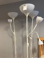 Photo showing three white floor lamps with tall stalks and large upward-facing bowls, plus smaller adjustable reading lamps attached.