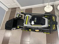 Overview top view of Ryobi lawn mower with grass bag, battery and charger