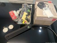 Mini portable RCA home theater projector, loose cables including RCA composite video and audio connectors, power adapter, and original product box visible on a table.