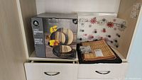 12-piece dinnerware set box and placemats stacked on a shelf