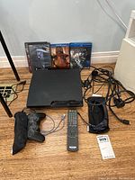 Lot arranged on hardwood floor with PlayStation 3 console and media items in clear view.