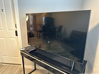 Front view of 50" Samsung TV on console with remote on top