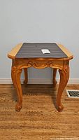 Front view of wooden side table showing carved legs and taped place mat on top