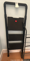Full image of 4ft foldable step ladder showing three wide black plastic steps and metal frame with rounded handles.