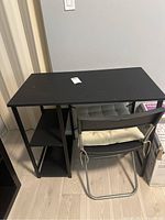 Angled view showing full black table with chair placed behind it.