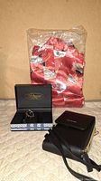 Photo shows a brand new Adriatica wristwatch in a black and white box, two black purses, and a red satin robe in packaging.