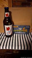 Photo showing the Moosehead Canada plastic beer bottle coin bank next to the Drinkopoly board game box.