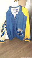 Front view of a blue and yellow Buffalo Sabres Starter jacket showing team logo patch on front pocket and script on sleeve.