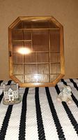 Photo of the wood and glass display cabinet with octagonal shape, standing vertically. Also shows the miniature house to the left and teddy bear to the right on a striped cloth.