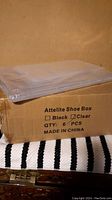 Stack of clear plastic shoe boxes on a cardboard box with packaging label showing brand Attelite, quantity originally 6 pieces, color clear, made in China.