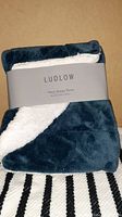 Folded new Ludlow velvet sherpa throw displaying velvet side and sherpa lining with label.