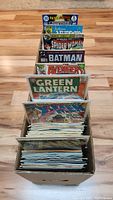 Box with various comic books visible arranged upright, showing multiple titles and covers.