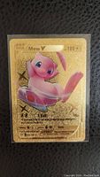 Front of Mew V Pokémon card with gold holographic finish showing character and stats.
