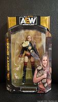 Front view of sealed AEW Dr. Britt Baker wrestling figure in original packaging with championship belt