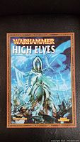 Front cover of Warhammer High Elves sourcebook showing armored High Elf warrior on horse with background art and title.