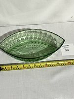 Oval green uranium glass bowl featuring diamond and starburst pattern with measurement tape showing approximately 12 inches length.