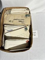 Cardboard box with numerous used envelopes showing stamps and postmarks.