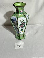 Front view of hexagonal vase showing floral and hummingbird handpainted panels with landscape scenes on sides.
