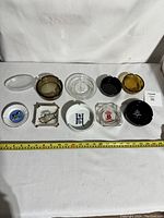 Top down view of all 10 ashtrays arranged in two rows on white background with ruler showing size