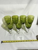 Set of 7 green wine glasses displayed with ruler for scale, showing uniform height and design.