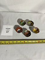 Top view showing all five saki cups arranged in a circular pattern with a measuring tape for scale.