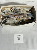 Shoebox filled with a large quantity of used postage stamps, many on torn pieces of envelopes.