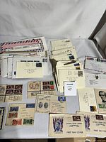 Top view of multiple envelopes and first day covers laid out on table, showing used stamps and handwritten addresses