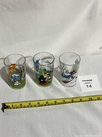 Set of three vintage Smurfs drinking glasses displayed front view with measuring tape showing approximately 4 inches tall.