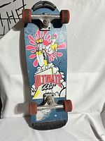 Skateboard front deck with 'Ultimate Air' graphic featuring glove and splash design, red wheels and silver trucks visible, blue background, some wear marks.