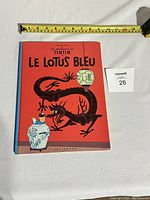 Front cover of the French Tintin comic book 'Le Lotus Bleu' showing red cover with dragon, lantern and Tintin illustration.
