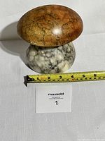 Mushroom-shaped alabaster bookend with measuring tape showing the width of the top around 6 inches and height of the base around 3 inches, displayed on white fabric.