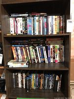 Three shelves filled with assorted DVDs and VHS tapes, showing a general overview of the collection.