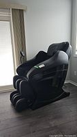 Side angle view of black massage chair next to window blinds