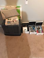 Full lot overview showing Wii Fit Plus box, Wii Play and Mario Kart Wii game boxes, accessory boxes, and loose cables and controllers.