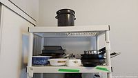 Wide shot of the kitchen shelf displaying multiple dishes and pans including Pyrex and cast iron pieces.