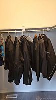 Overview of the lot showing the hanging jackets and clothing items on hangers in a closet