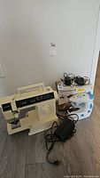 Full view of the Singer 6215C sewing machine and Dressmaker II mini sewing machine with accessories and original box on floor.
