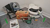 Wide shot of the three items showing the Cuisinart meat slicer, T-fal Actifry, and apple corer and slicer with box