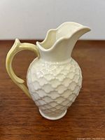 Side front view showing textured body, spout shape, and yellow handle