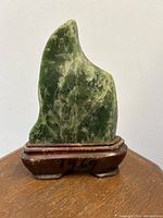 Front view of green nephrite jade carved in shark tooth form on rosewood stand with 1969 Taipei inscription.
