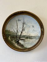 Head-on view of circular framed oil painting showing full gilt frame and landscape scene.