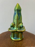 Front view of the iridescent green eosin Zsolnay Hungarian tower sculpture showing tall pointed form and flared base with two floral motifs