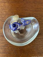 Top view showing the clear glass dish with the blue and gold spangled fish inside.