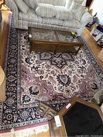 Wool area rug under a sofa and wooden coffee table showing overall design and condition.