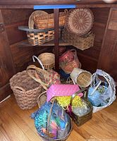Multiple woven baskets of various sizes and colors arranged under a wooden shelf on a hardwood floor