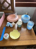 Full grouping of bath accessories including Yeager soap dish, blue floral covered dish and tumbler, small cup, yellow dish, trinket box and figurine.
