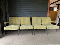 Front view of the four connected modular sofa sections showing yellow-green plaid upholstery and metal legs.